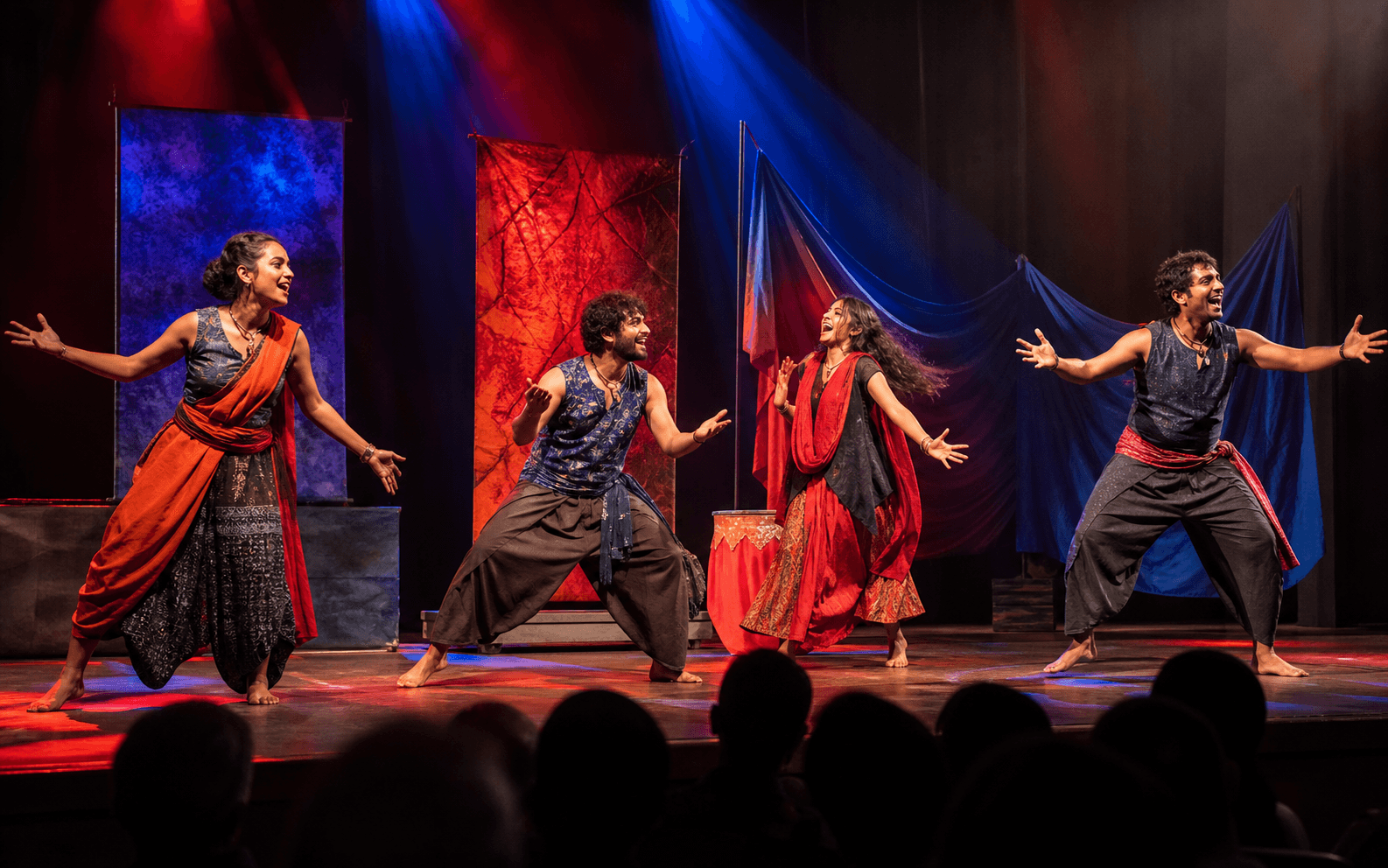 Four theatre performers in a colourful ensemble stage performance